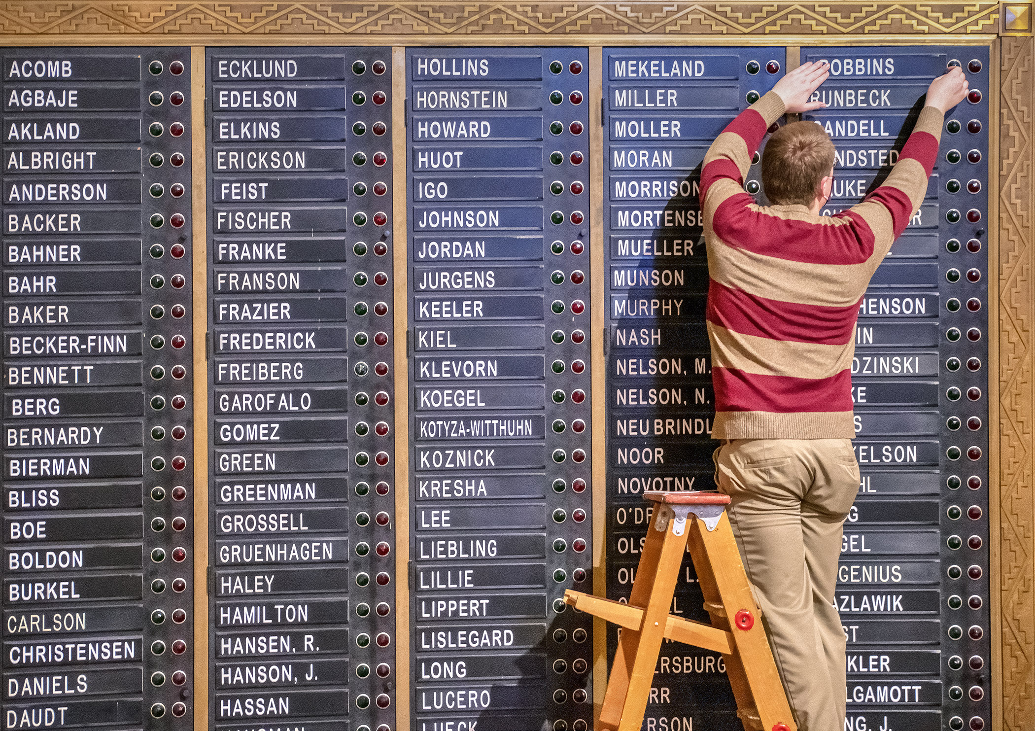Travis Roline, administrative assistant for the Chief Clerk’s Office, adjusts nameplates on the House voting board Dec. 29 in preparation for the start of the 2021 legislative session. Photo by Andrew VonBank